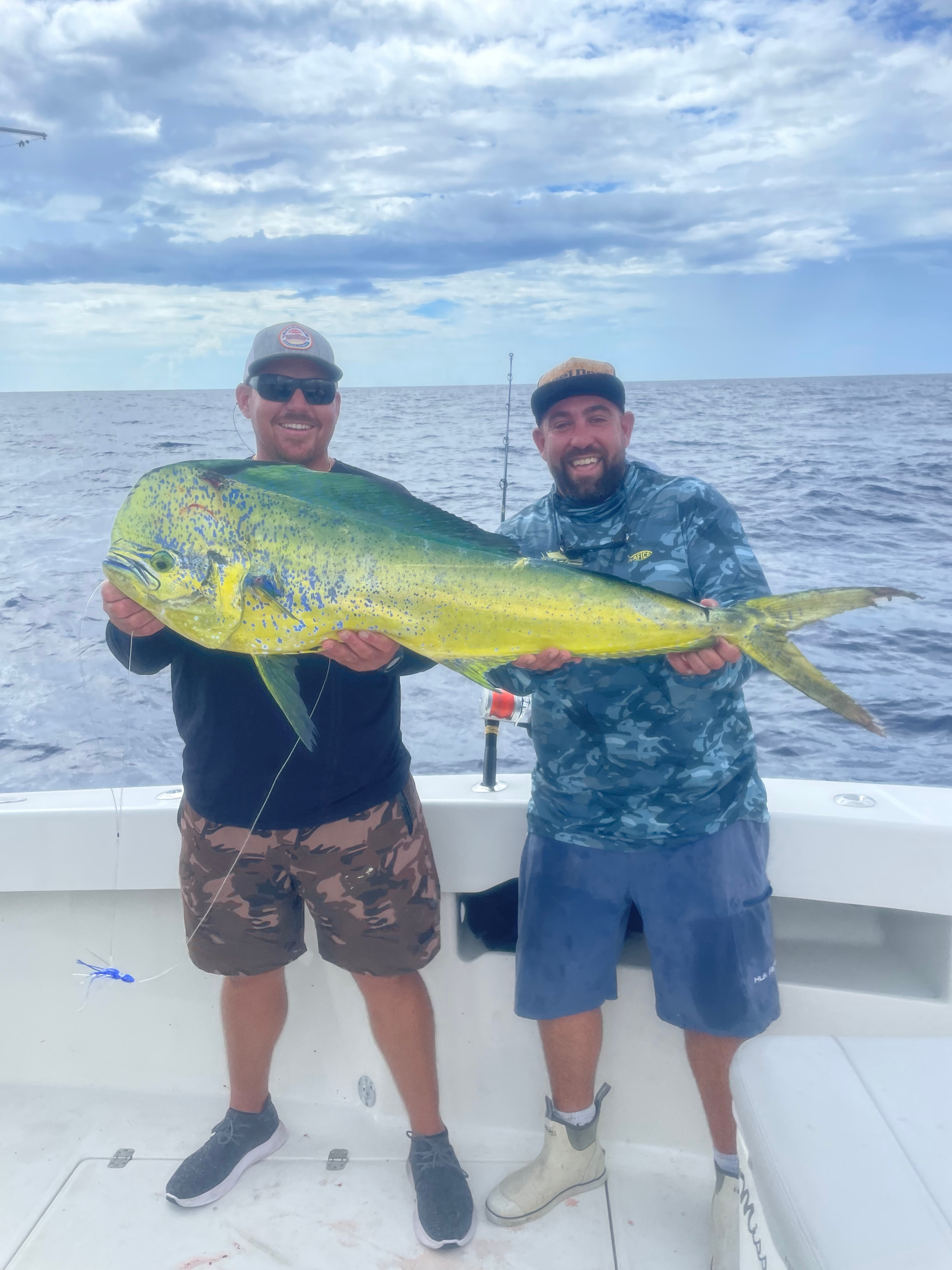 Two anglers holding a massive mahi-mahi caught trolling off Miami